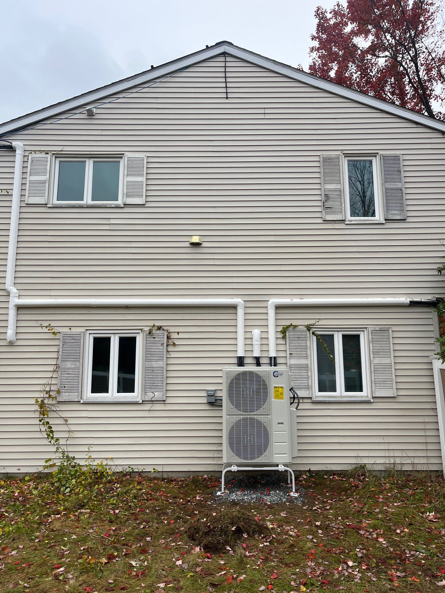 Exterior of a two-story building with white siding, windows, and an outdoor HVAC unit.