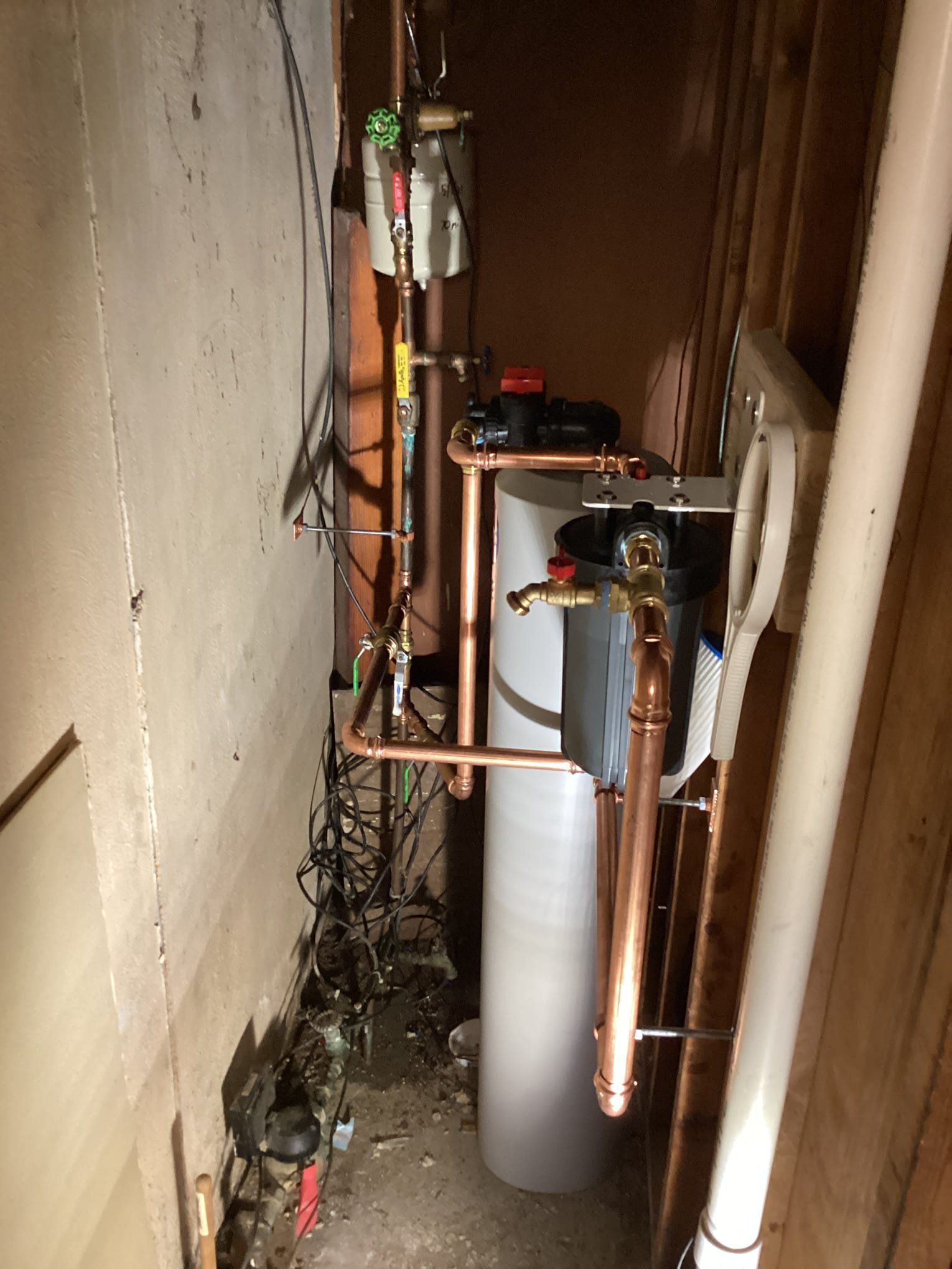 Water softener system with copper piping in a utility closet.