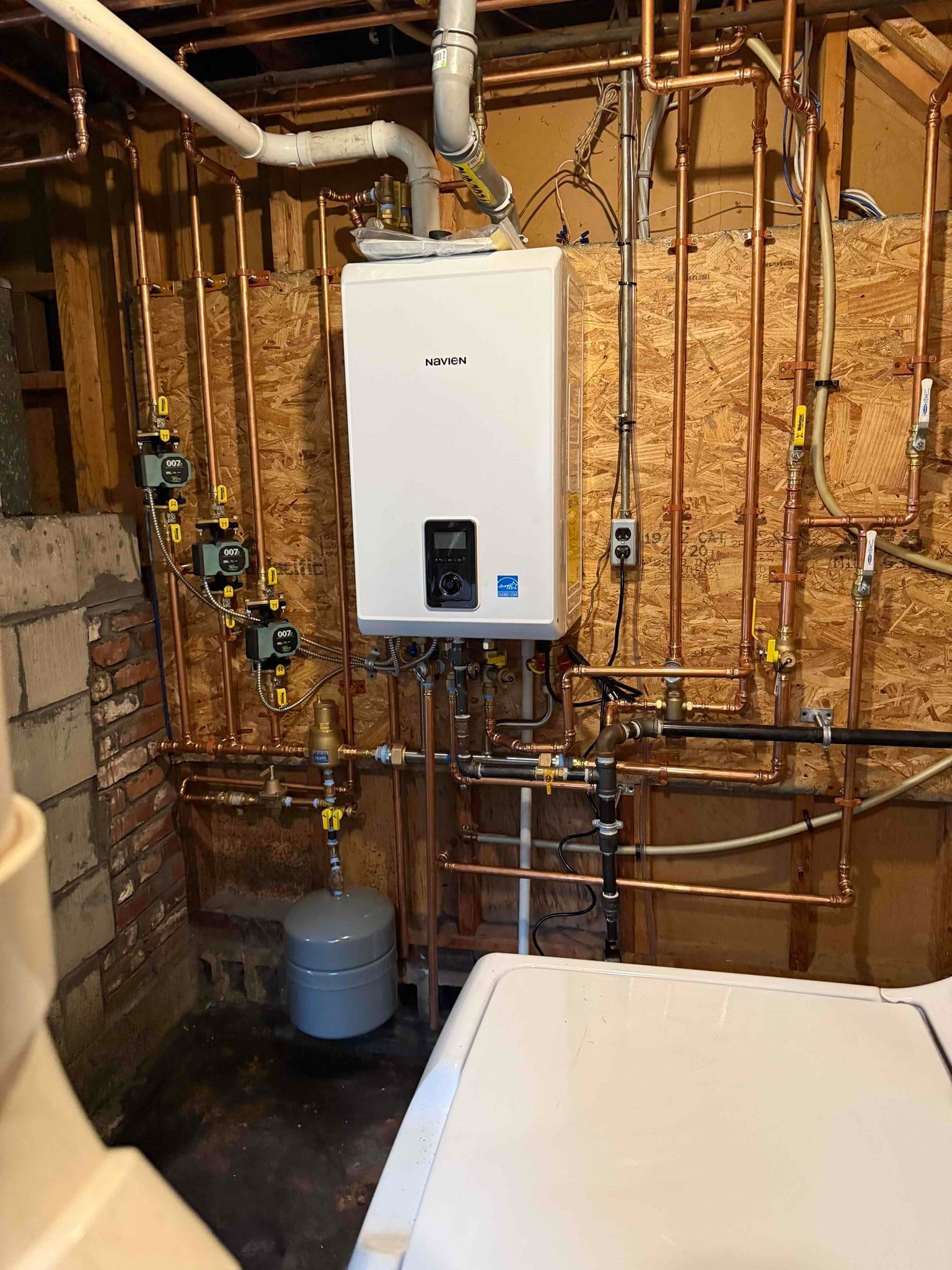 Copper pipes and white water heater in a basement.