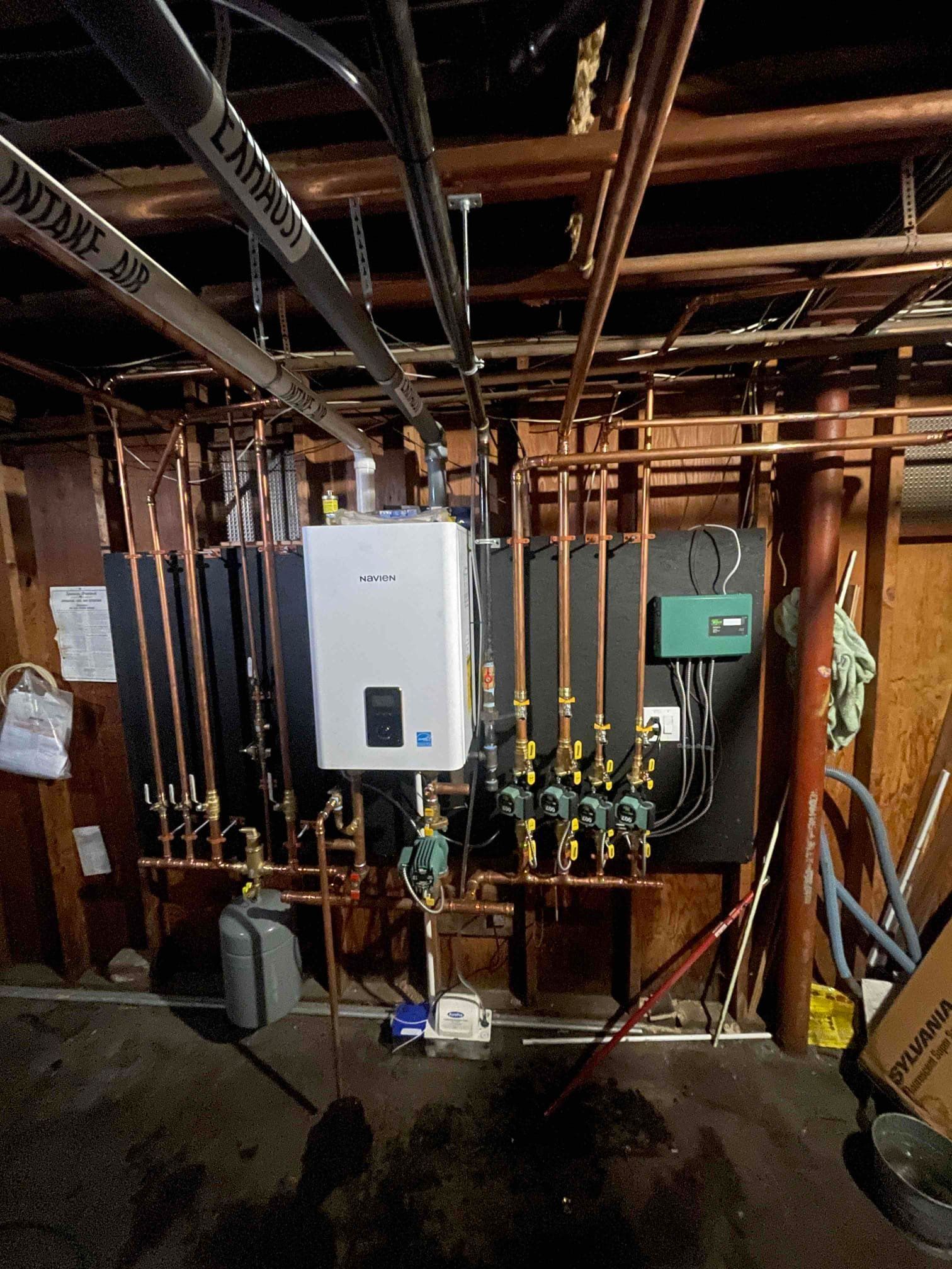 Copper pipes and heating equipment installed on a wooden wall.