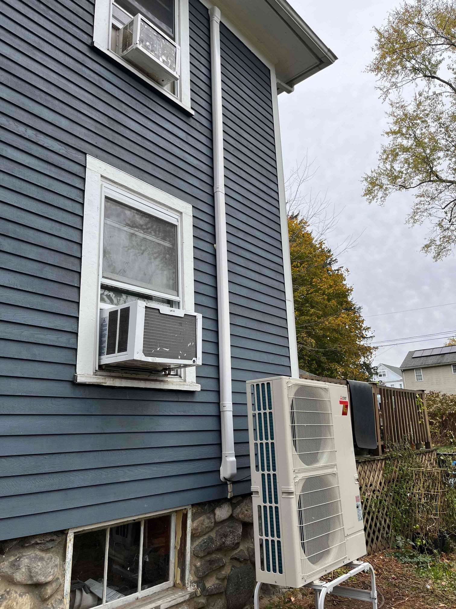 Blue house exterior with air conditioning units and a white pipe.