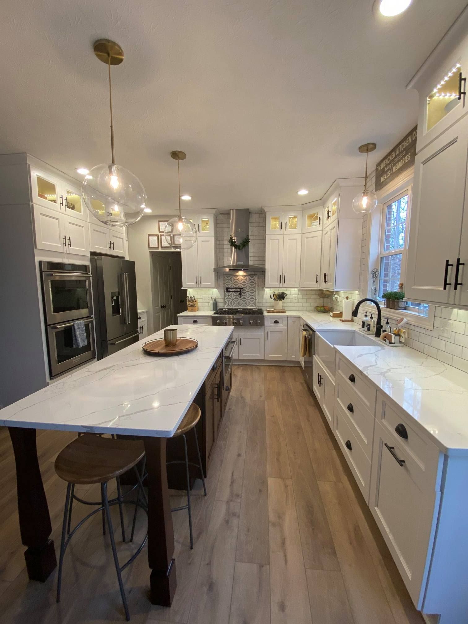 A kitchen with white cabinets and a large island in the middle.