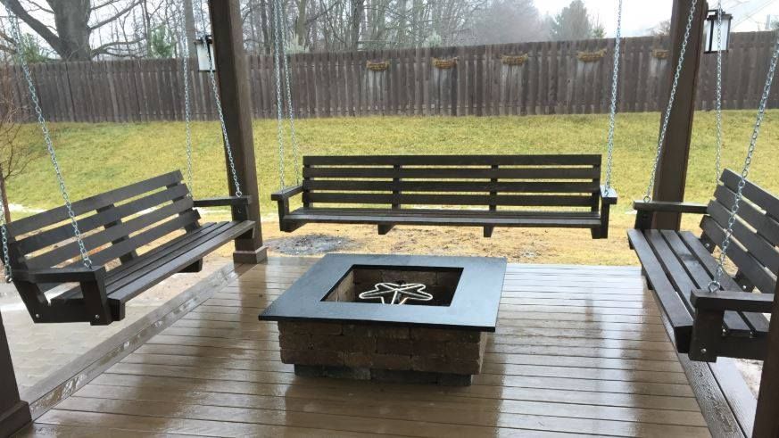 A wooden porch with swings and a fire pit.