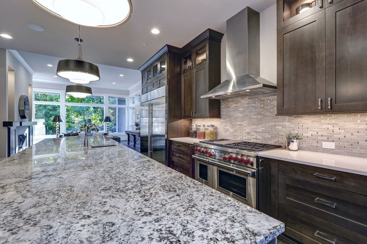 A kitchen with granite counter tops and stainless steel appliances.