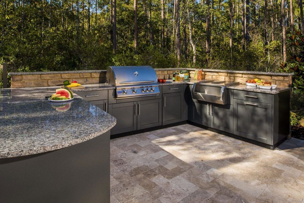 A large outdoor kitchen with a grill and watermelon on the counter.