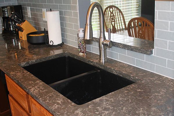 A kitchen counter with a black sink and a faucet.