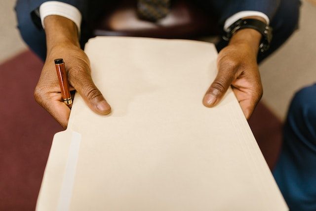 person holding an tan folder with documents inside