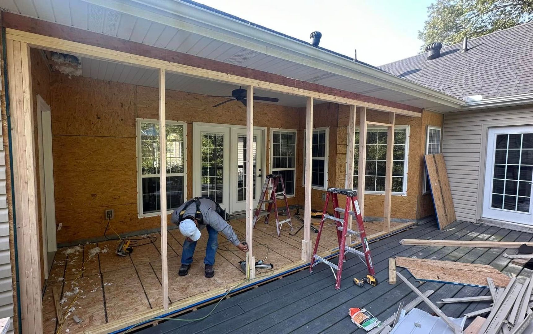 Two construction workers are working on a building in a parking lot.