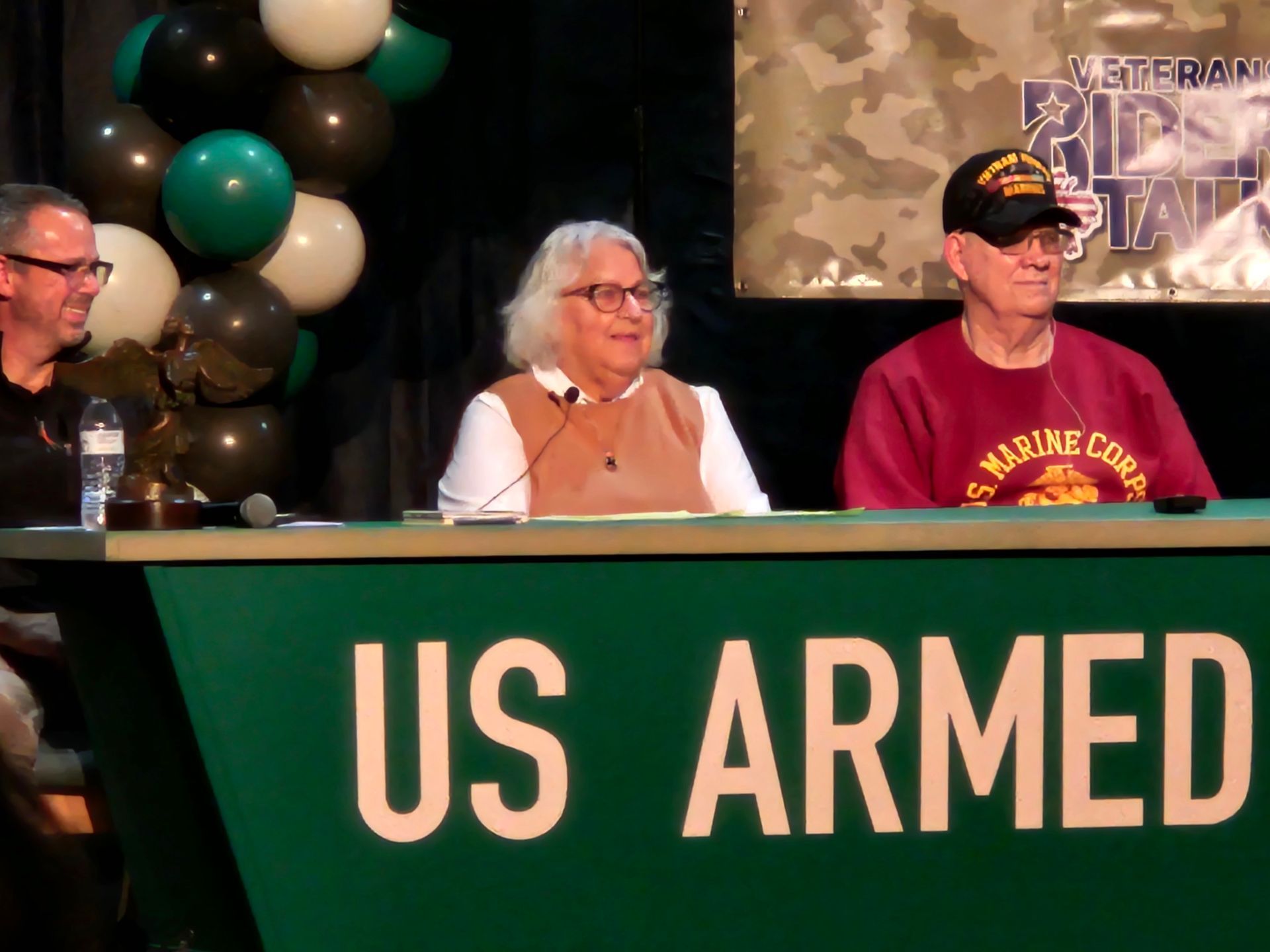Three people seated at a green table with 