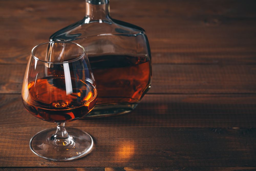 Glass of Amber Liquor and a Decanter on a Wooden Surface — BYO Cellars in Forster, NSW