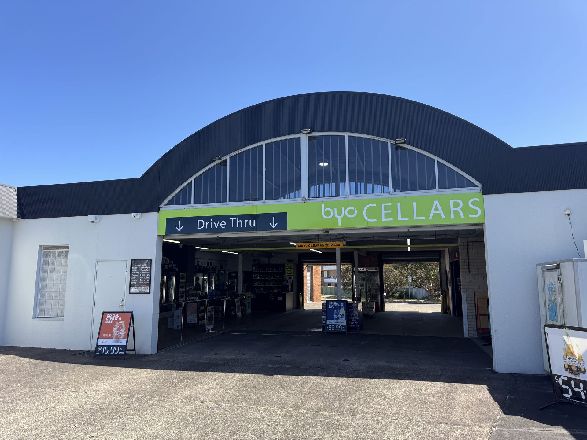 Exterior of a BYO Cellars liquor store, drive-thru entrance under arched roof — BYO Cellars