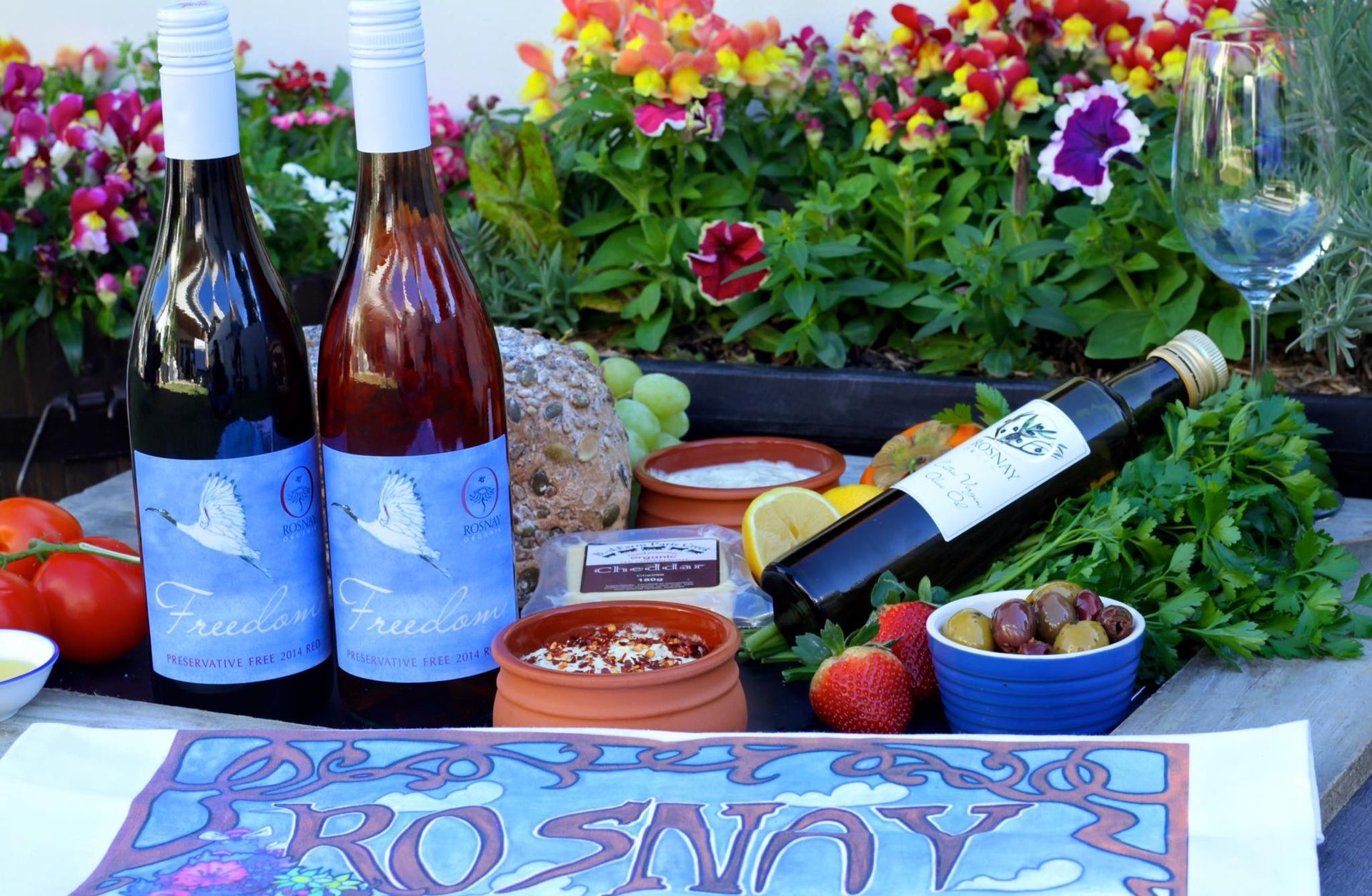 Bottles of Wine, Food, and Flowers on a Table Outdoors — BYO Cellars in Fennell Bay, NSW