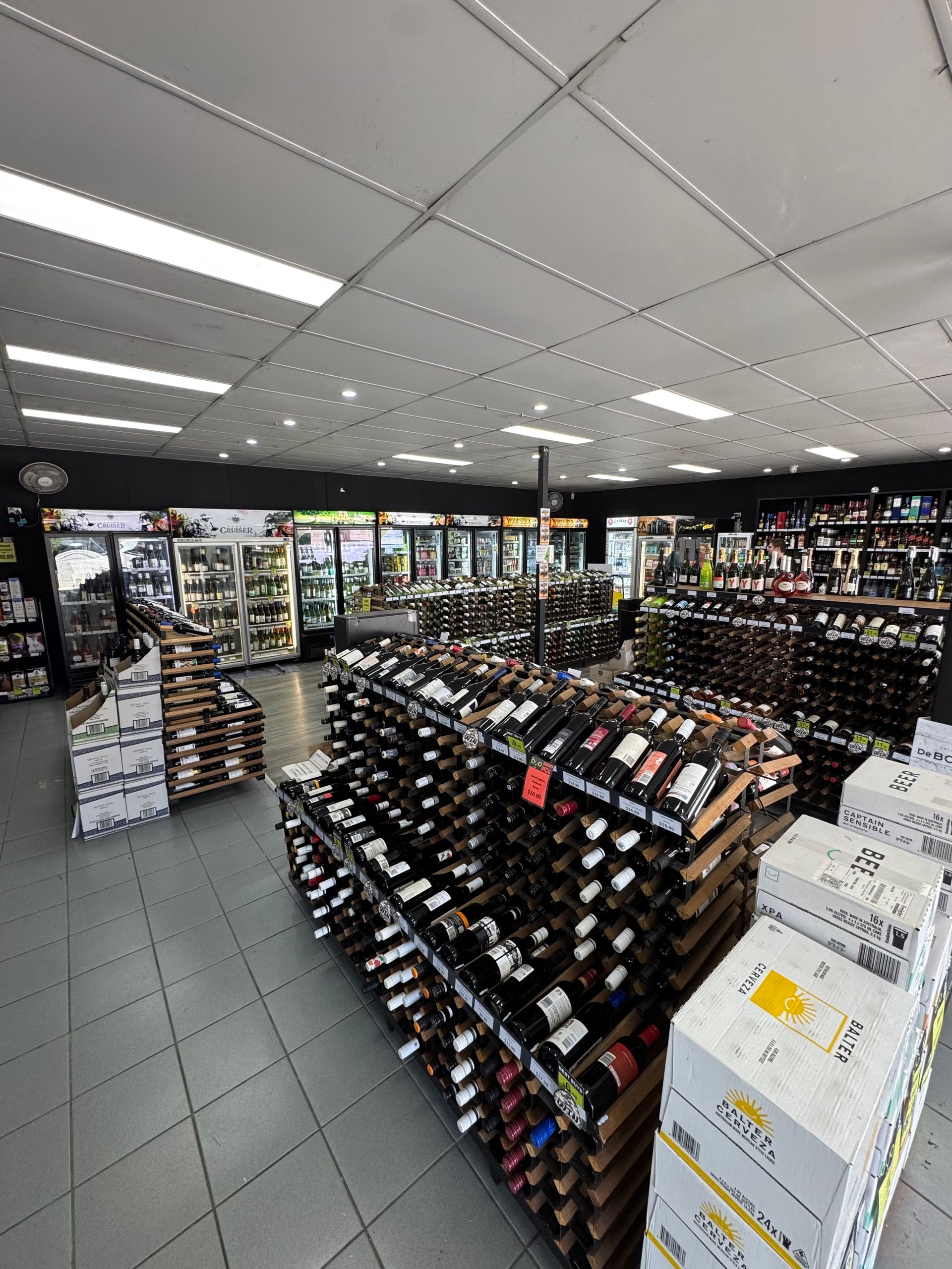 Liquor store interior with wine bottles on display shelves and refrigerated sections — BYO Cellars