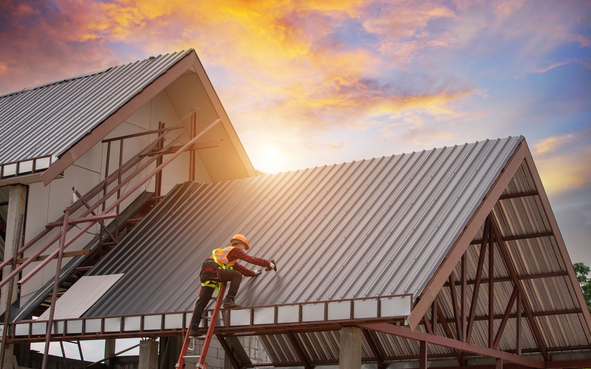 A construction worker is working on the roof of a house.