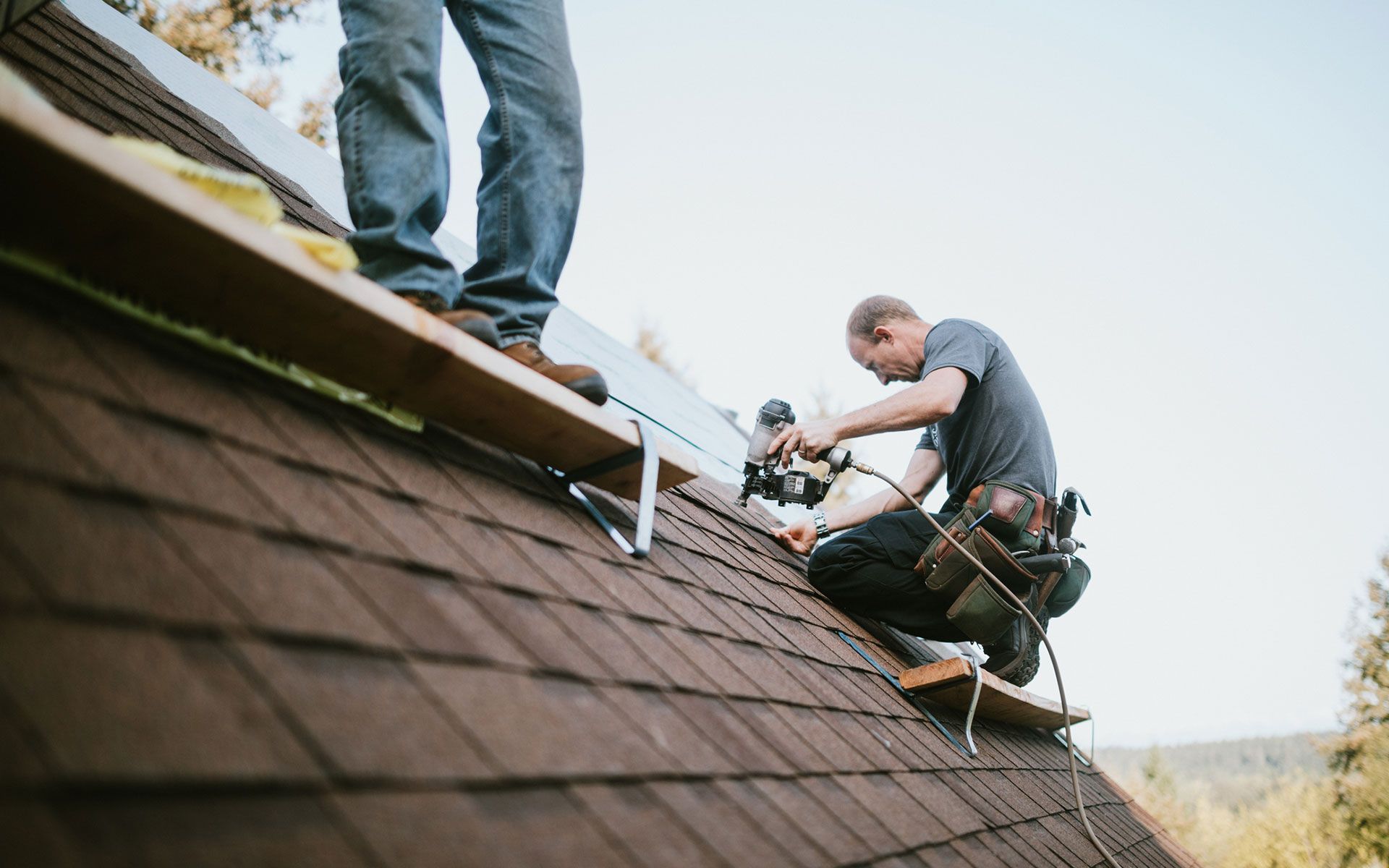 Two men are working on the roof of a house.