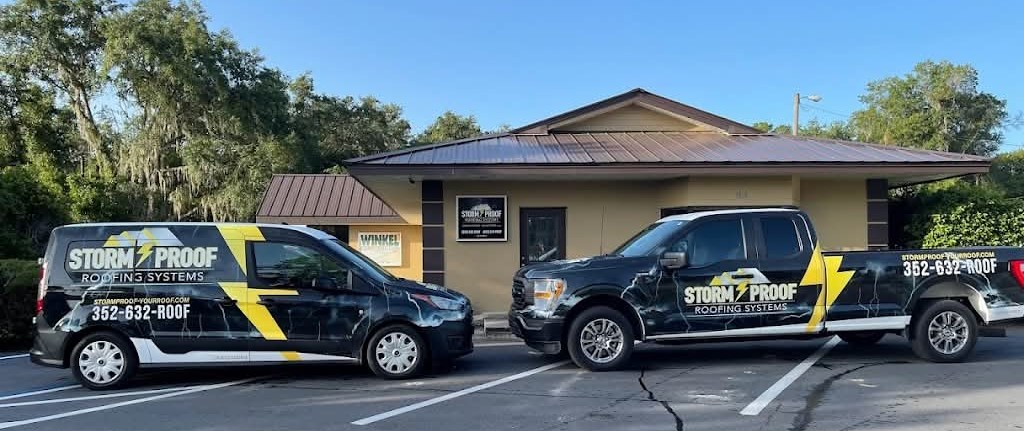 Two company vehicles parked in front of a building with a sign. The vehicles are black with yellow lightning bolts on them.