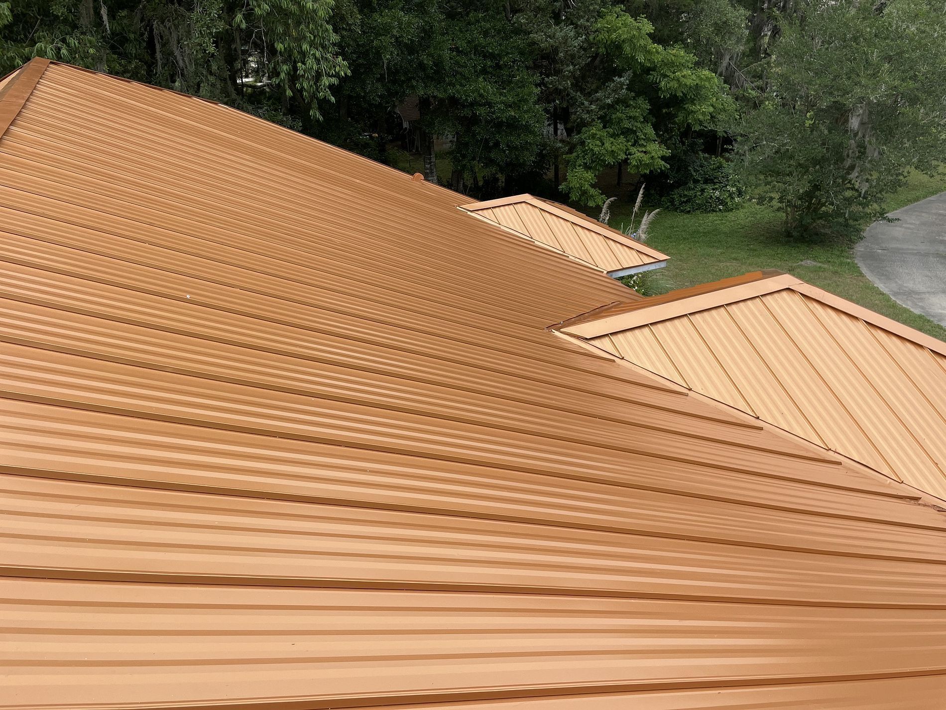 Brown metal roof angled toward the viewer, with trees in the background.