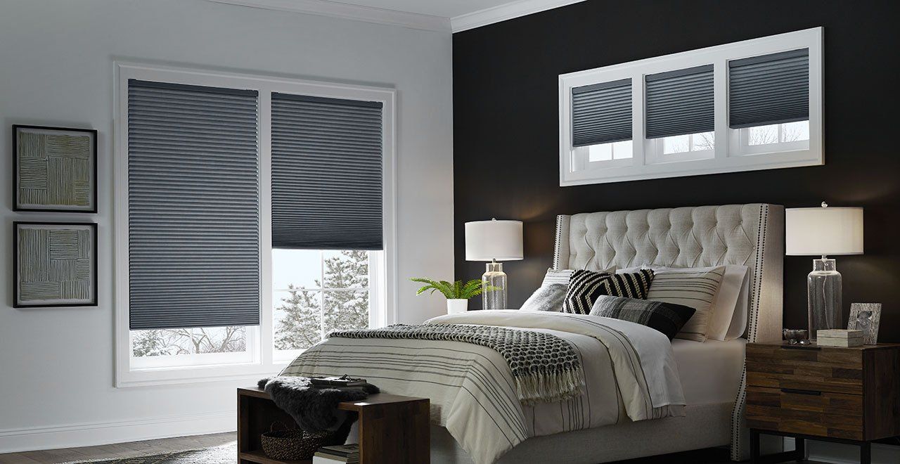 A bedroom with a bed , nightstand , lamps and black walls.