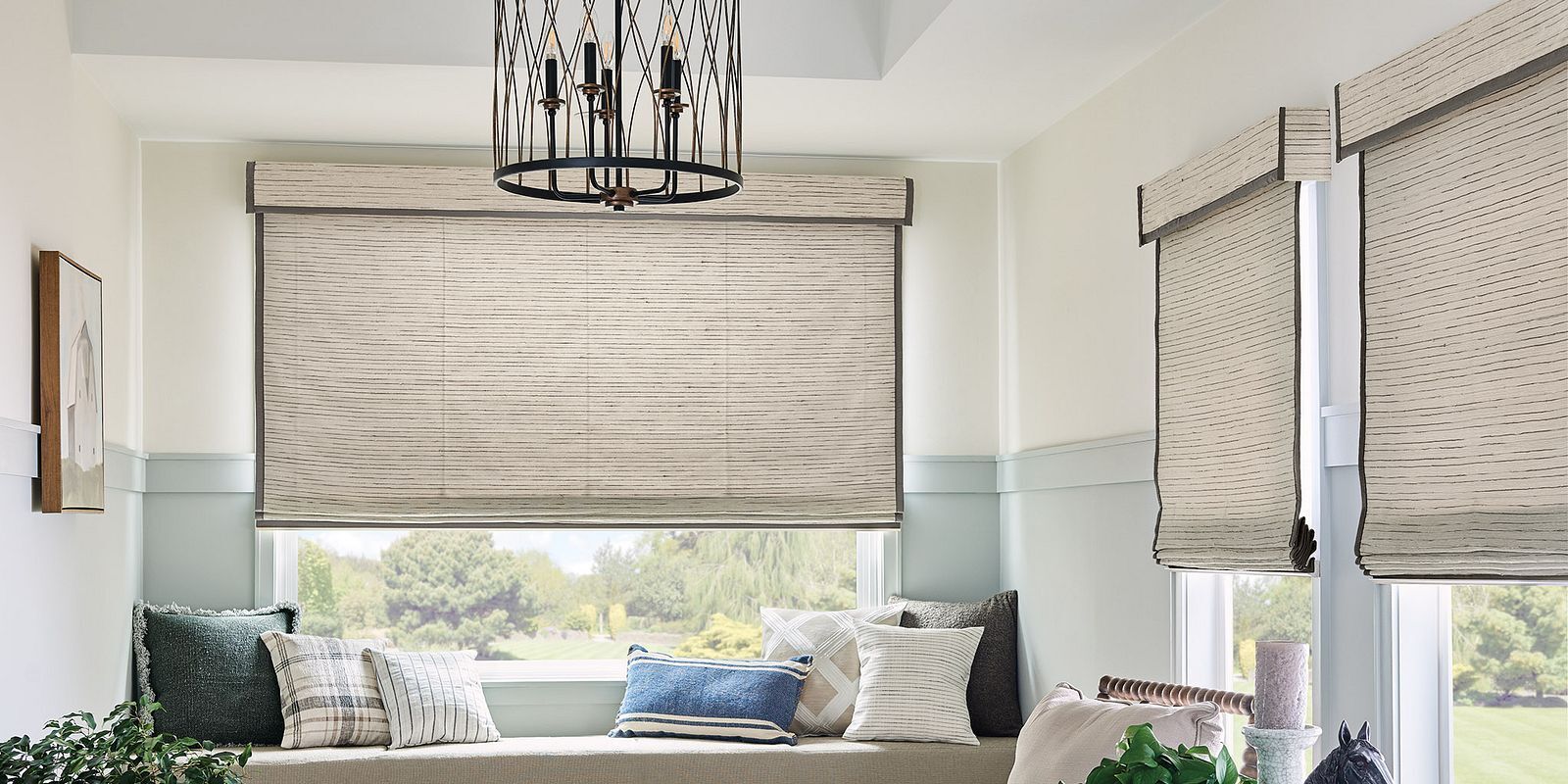 A living room with a window seat and roman shades.