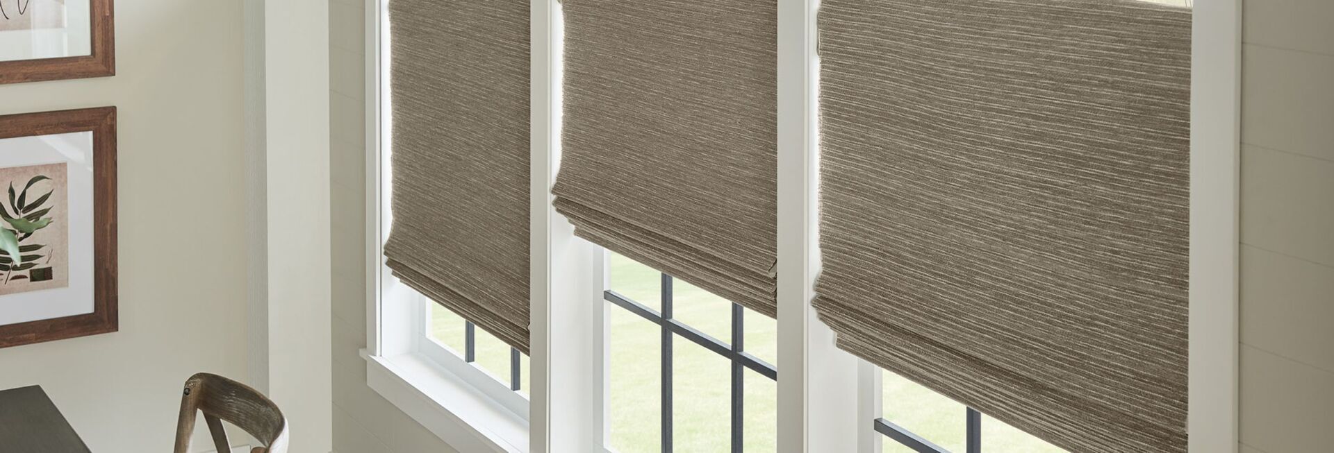 A room with three windows and roman shades on them.