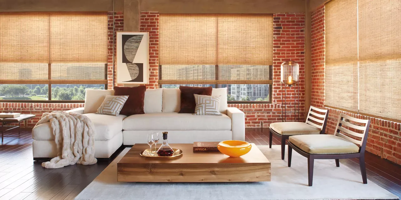 A living room with a couch , coffee table , chairs and a brick wall.