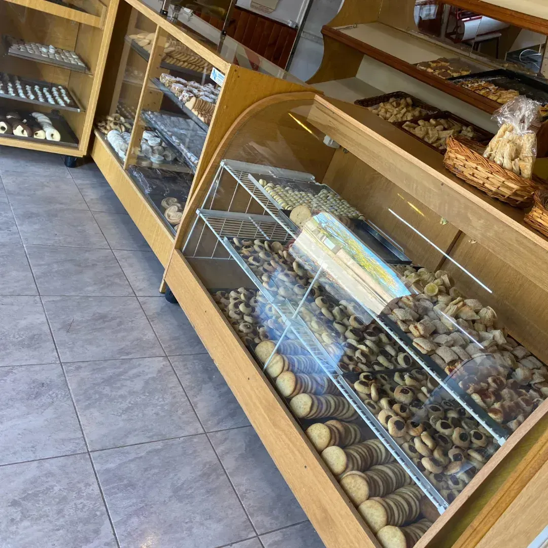 Vitrina de panadería de madera llena de diversos productos horneados sobre un piso de baldosas.