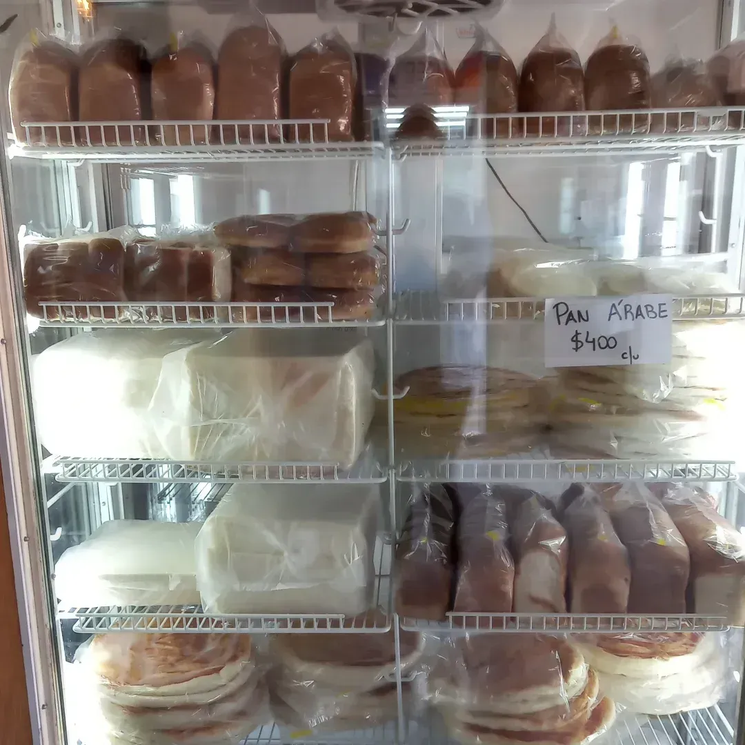 Vitrina refrigerada repleta de diversos productos horneados envasados, incluidos pan, pasteles y panqueques.