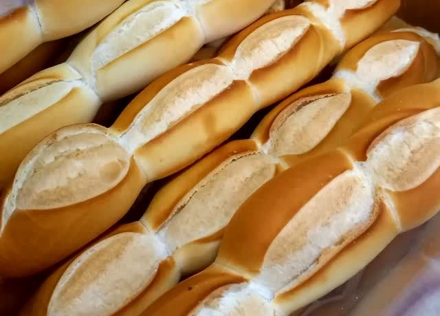 Hileras de hogazas de pan francés de color marrón dorado, con la parte superior marcada con marcas blancas.