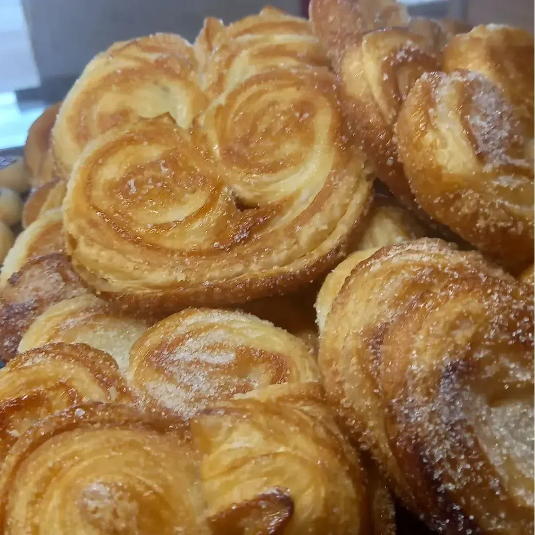 Pila de palmiers dorados cubiertos de azúcar, una masa hojaldrada con forma de espiral.