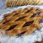 Pastel con cubierta enrejada y relleno oscuro, espolvoreado con azúcar glas.