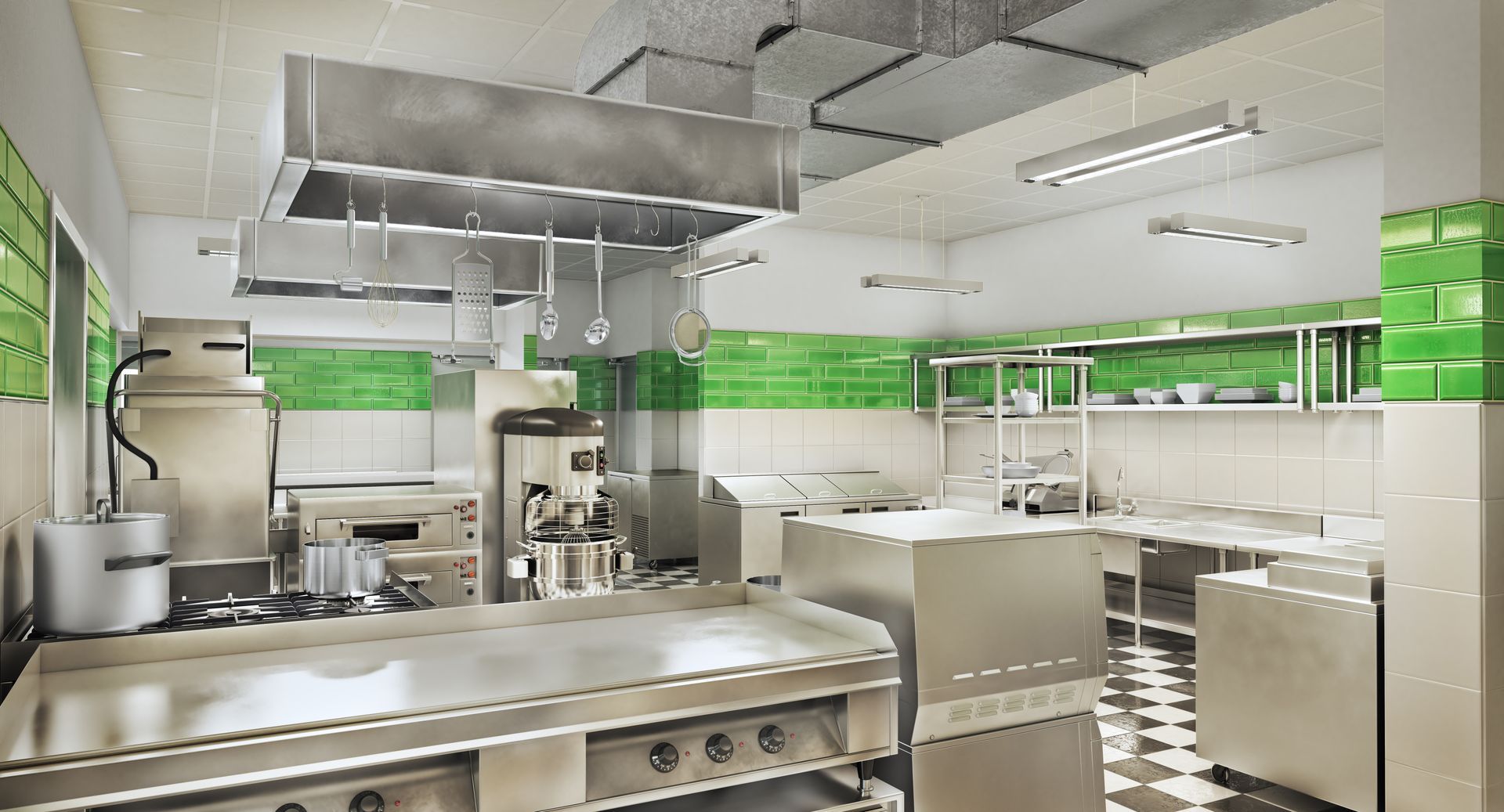 An empty commercial kitchen with stainless steel appliances and green tiles.