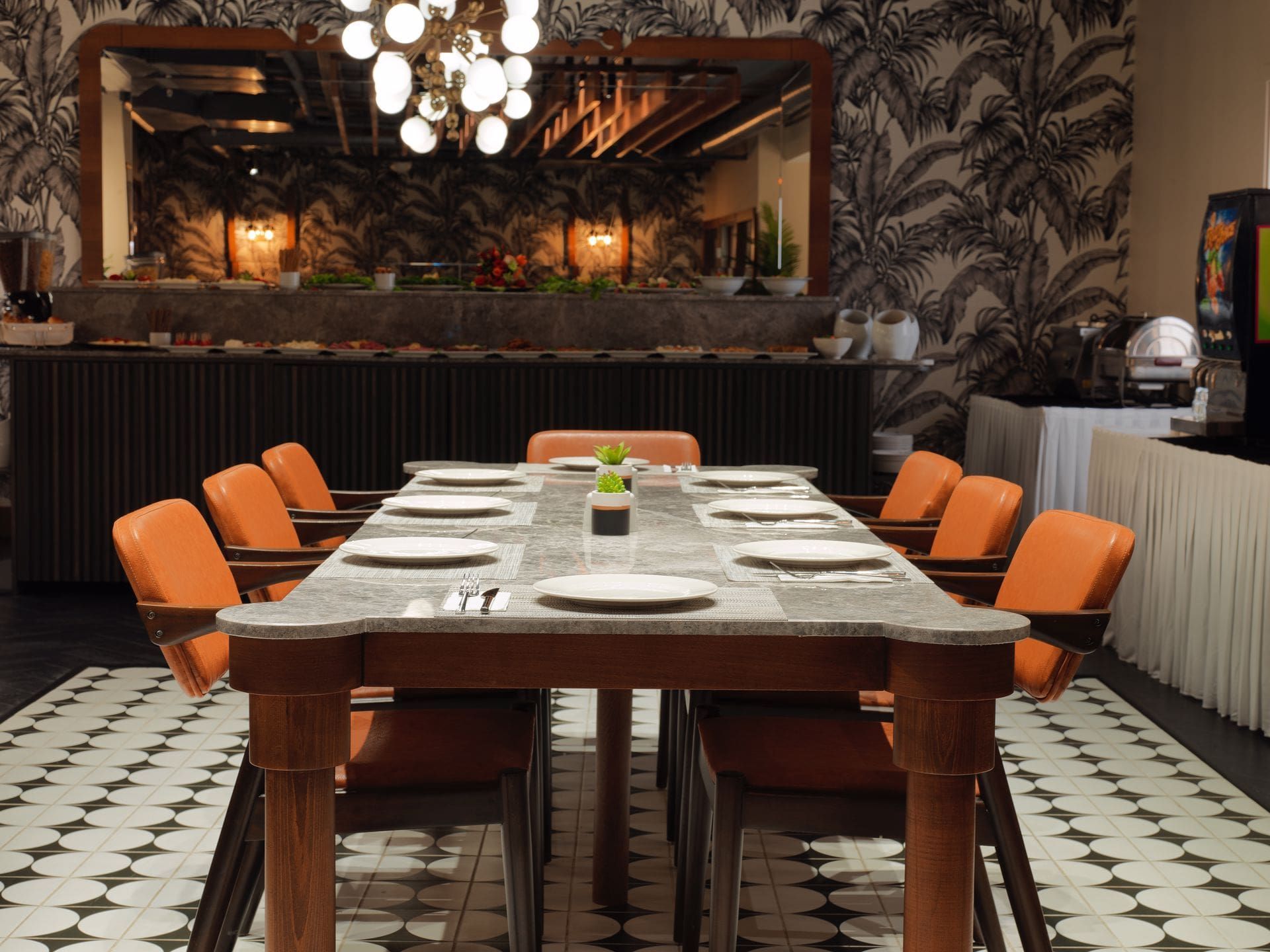 A long table with plates and chairs in a restaurant.