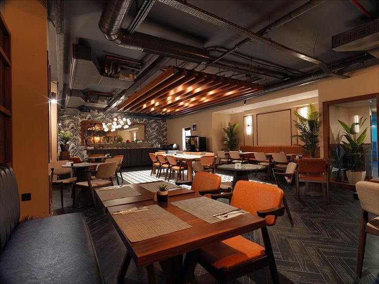 A restaurant with tables and chairs and a bar in the background.