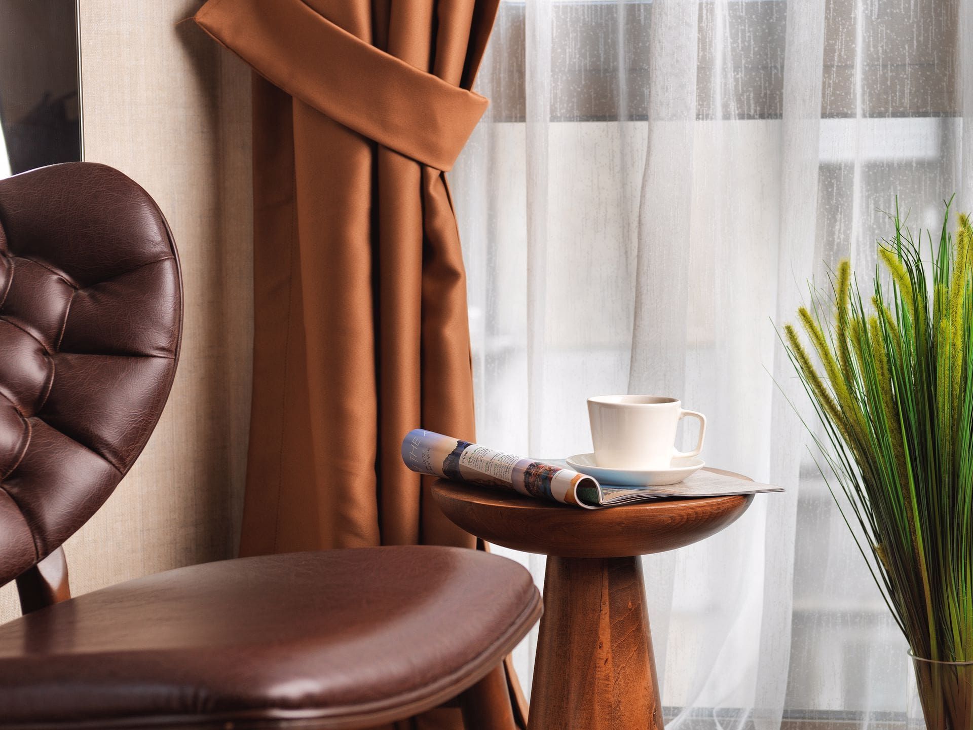 A chair is sitting next to a table with a cup of coffee on it.