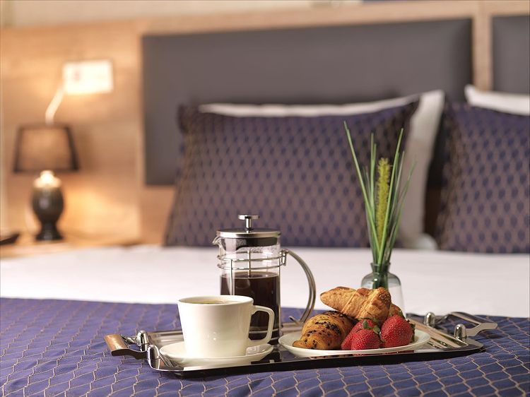 A bed with a tray of food and a cup of coffee on it