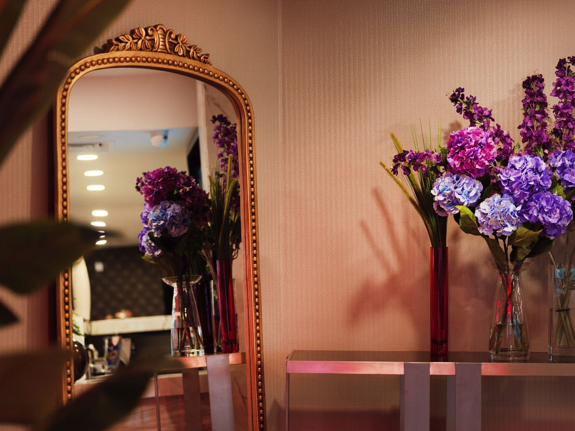 A mirror with purple flowers in vases in front of it