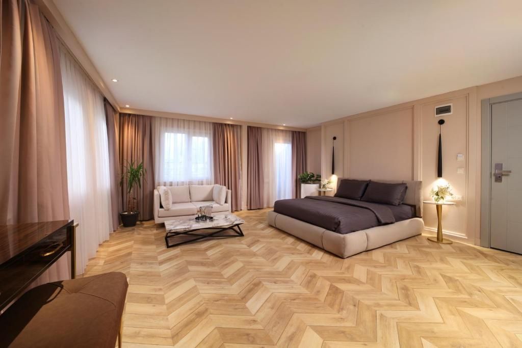 A bedroom with a large bed , couch , table , and curtains.