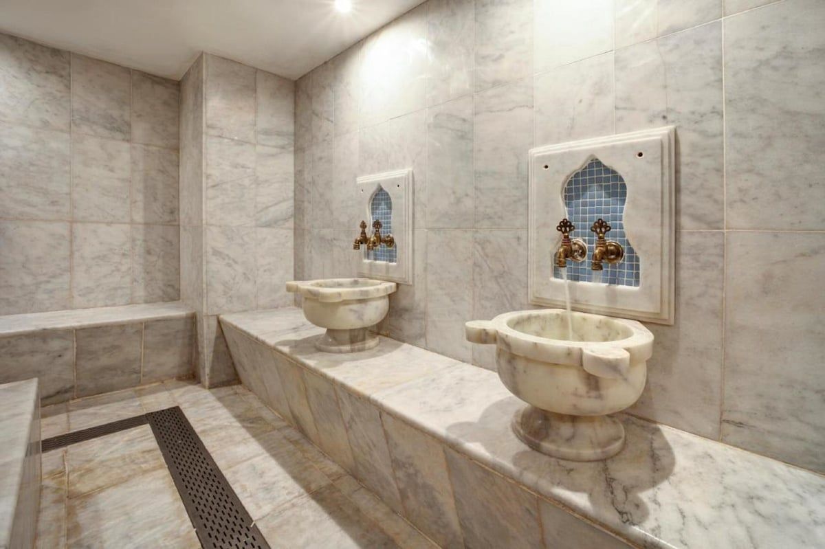 A bathroom with two sinks and two faucets on the wall.
