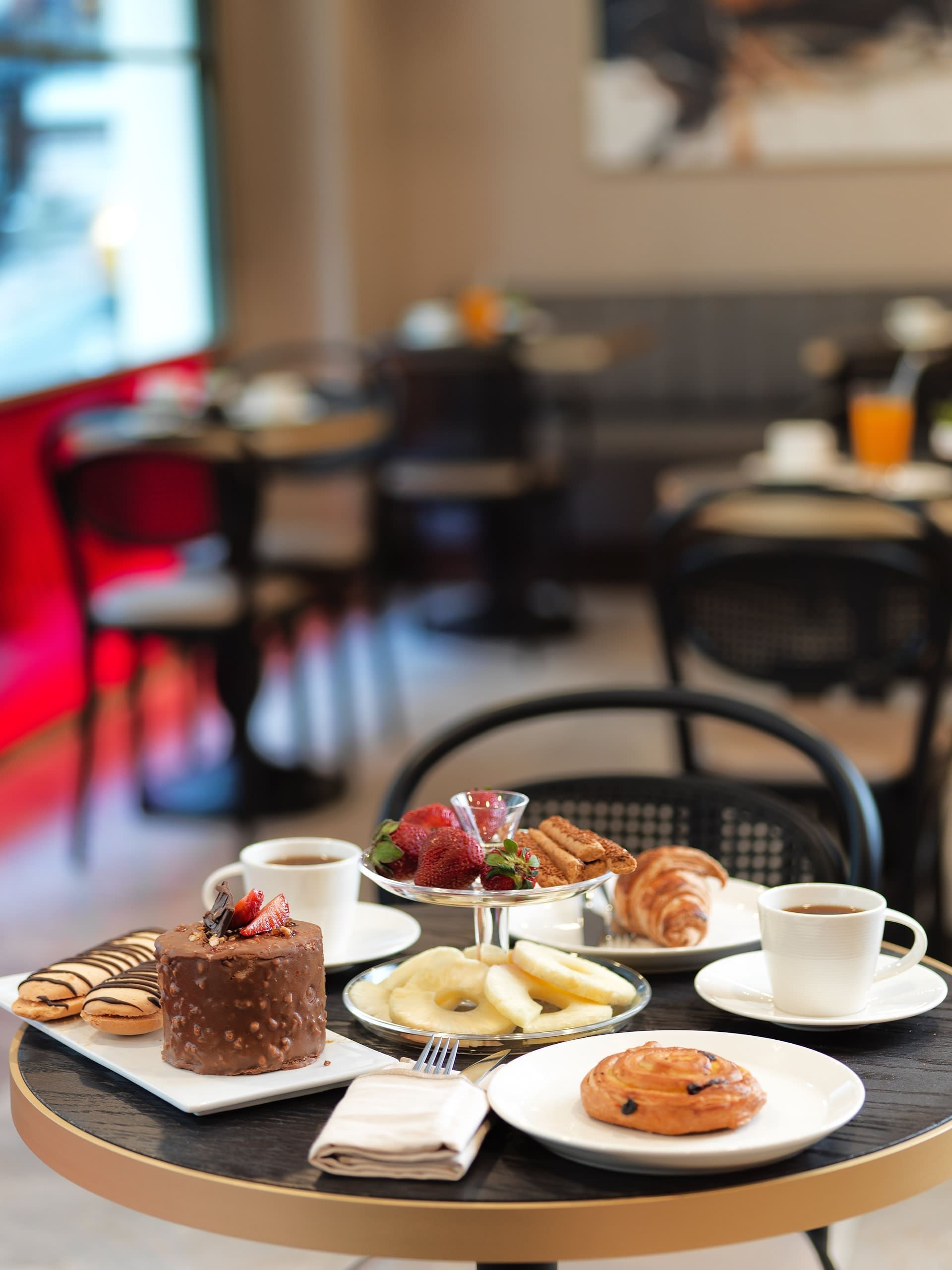 A table with plates of food and cups of coffee on it