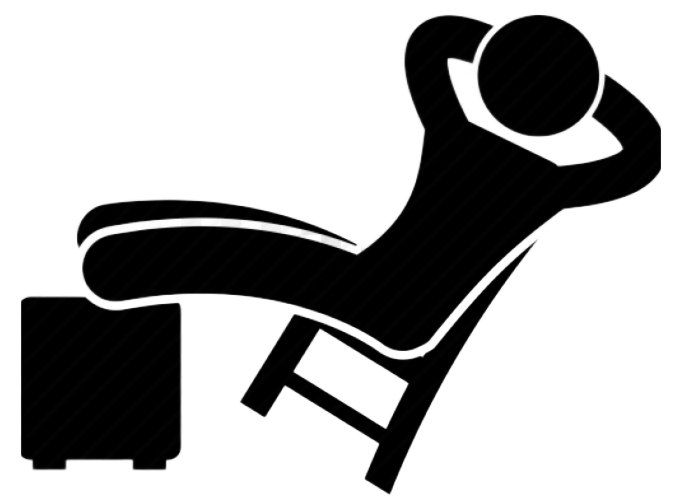 Person reclining in chair with feet on a footstool, arms behind head.