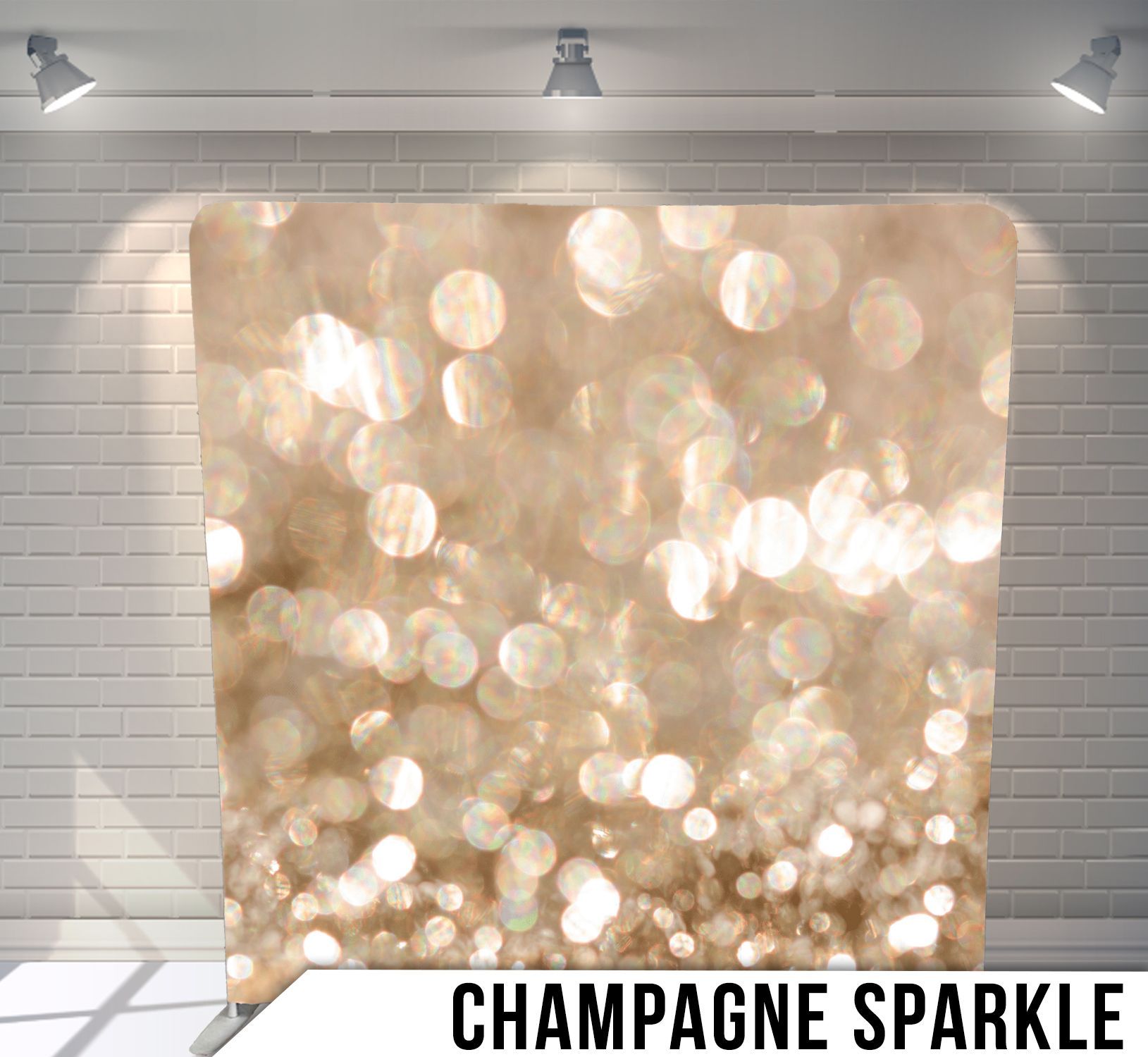 Champagne sparkle backdrop for photos against a white brick wall, lit by spotlights.