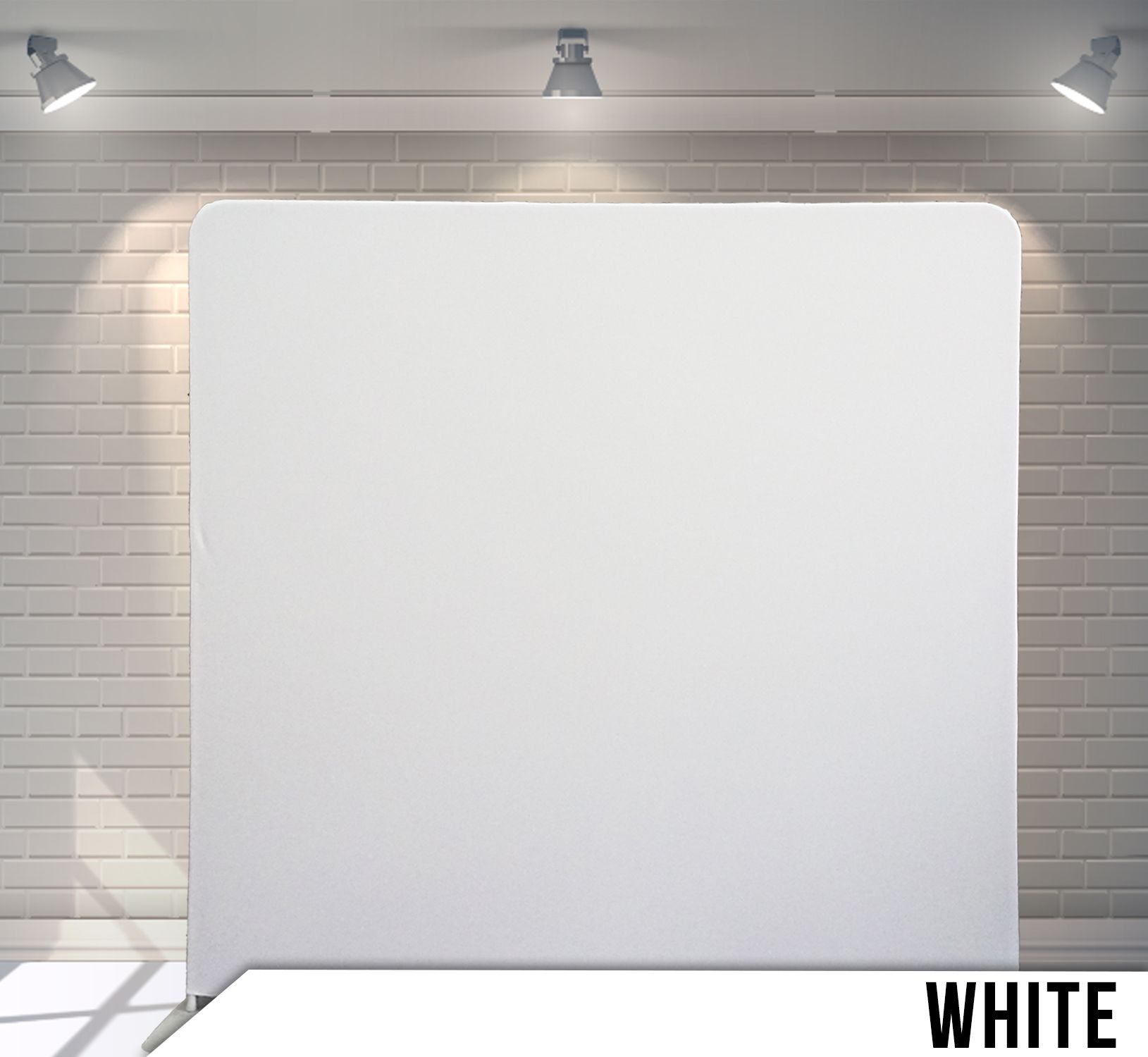 White backdrop with rounded corners, lit by overhead spotlights, against a brick wall.