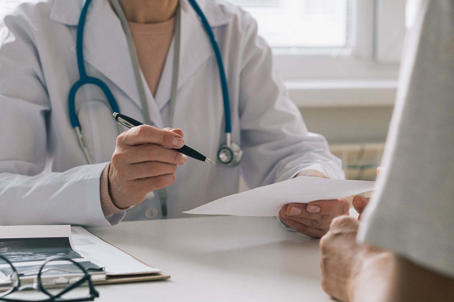 A doctor is talking to a patient while holding a piece of paper.