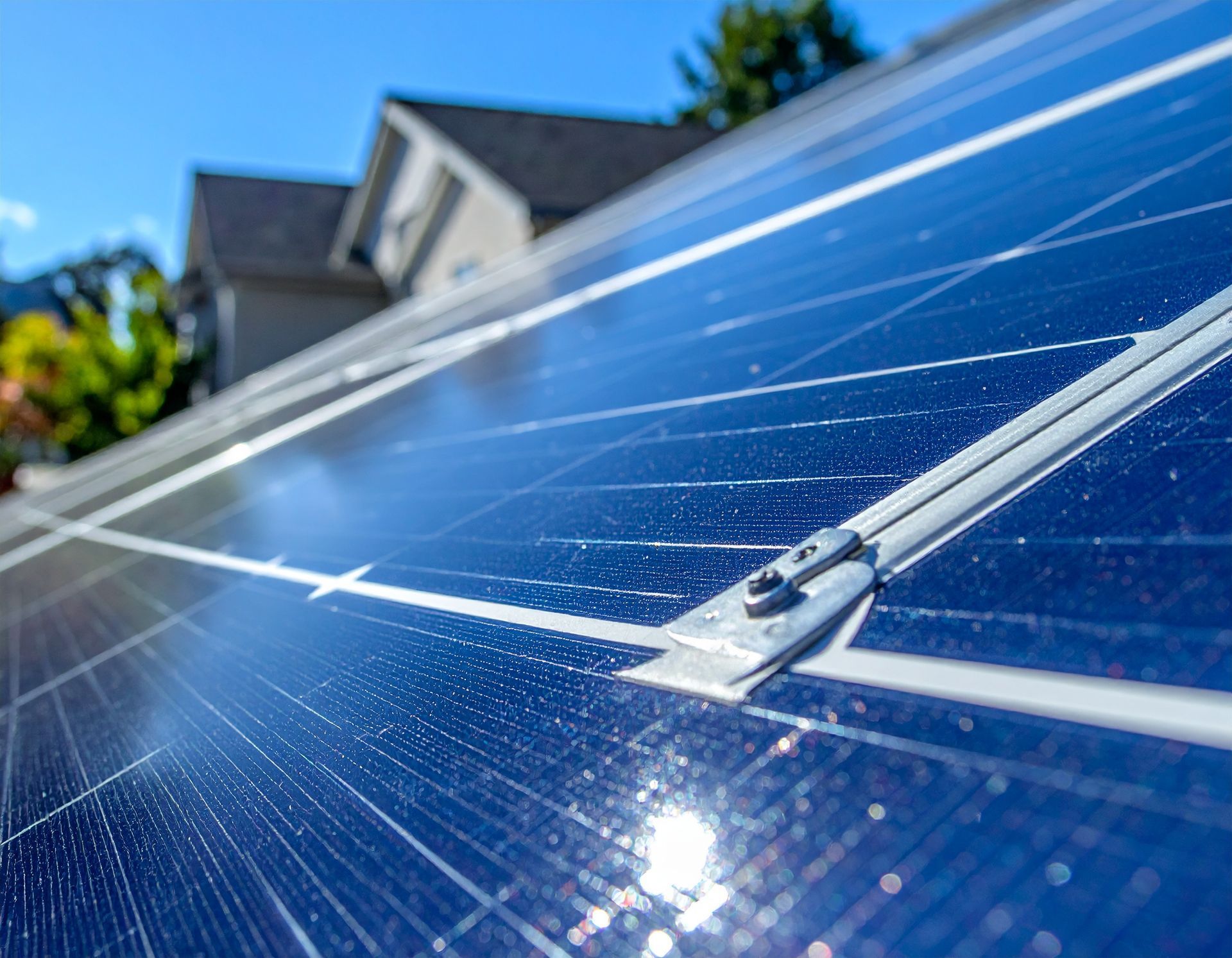 Close-up of blue solar panels on a residential rooftop under a clear sky.