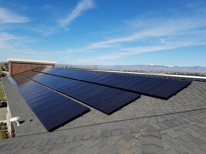 Solar panels on a residential roof, angled toward the sky on a sunny day.