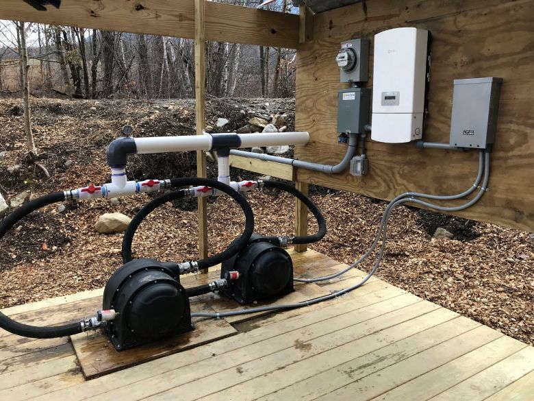 Pipes with pumps and valves in a stone-walled room.