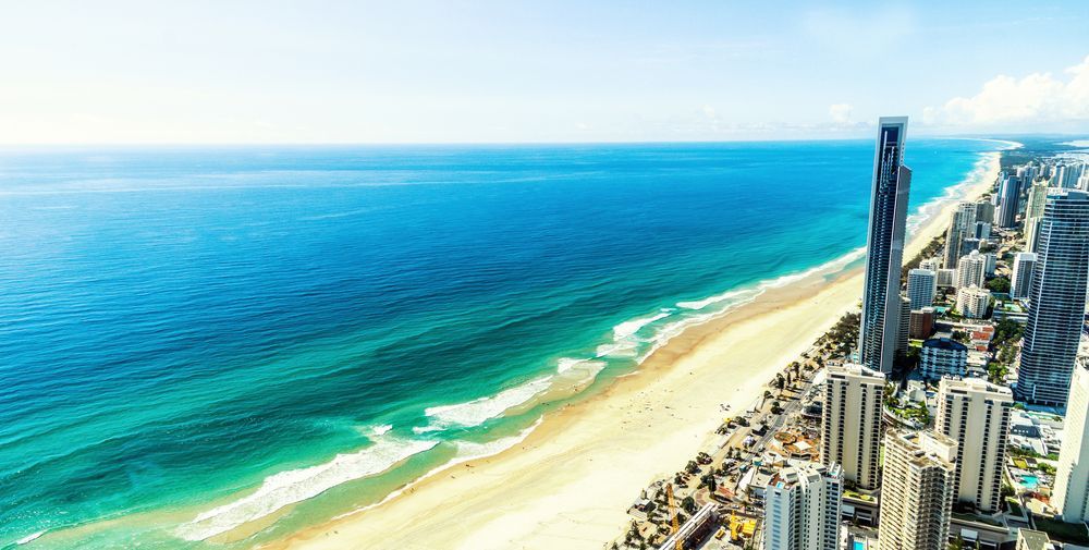 Beachfront cityscape with blue ocean, sandy shore, and high-rise buildings.