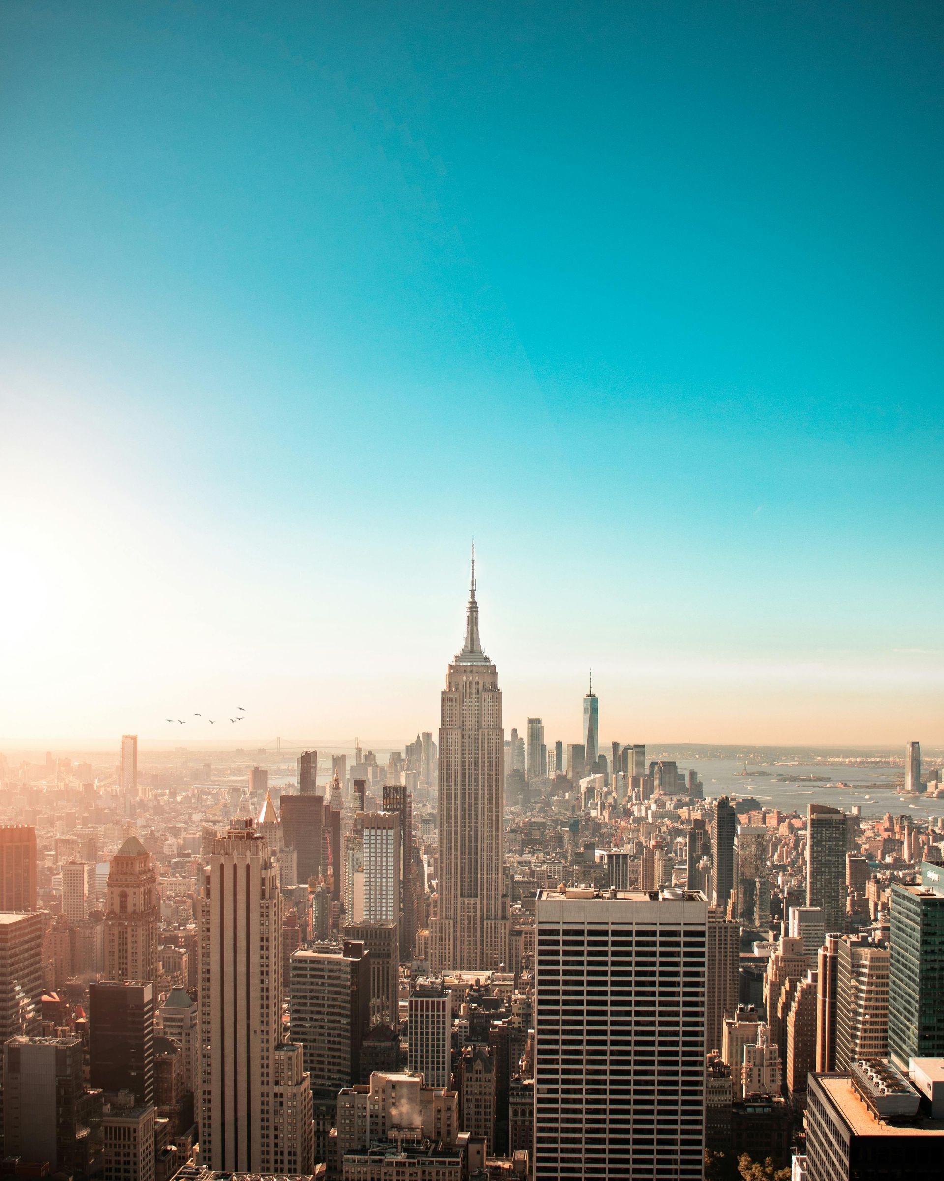 Empire State Building dominates a New York City skyline with a clear blue sky.