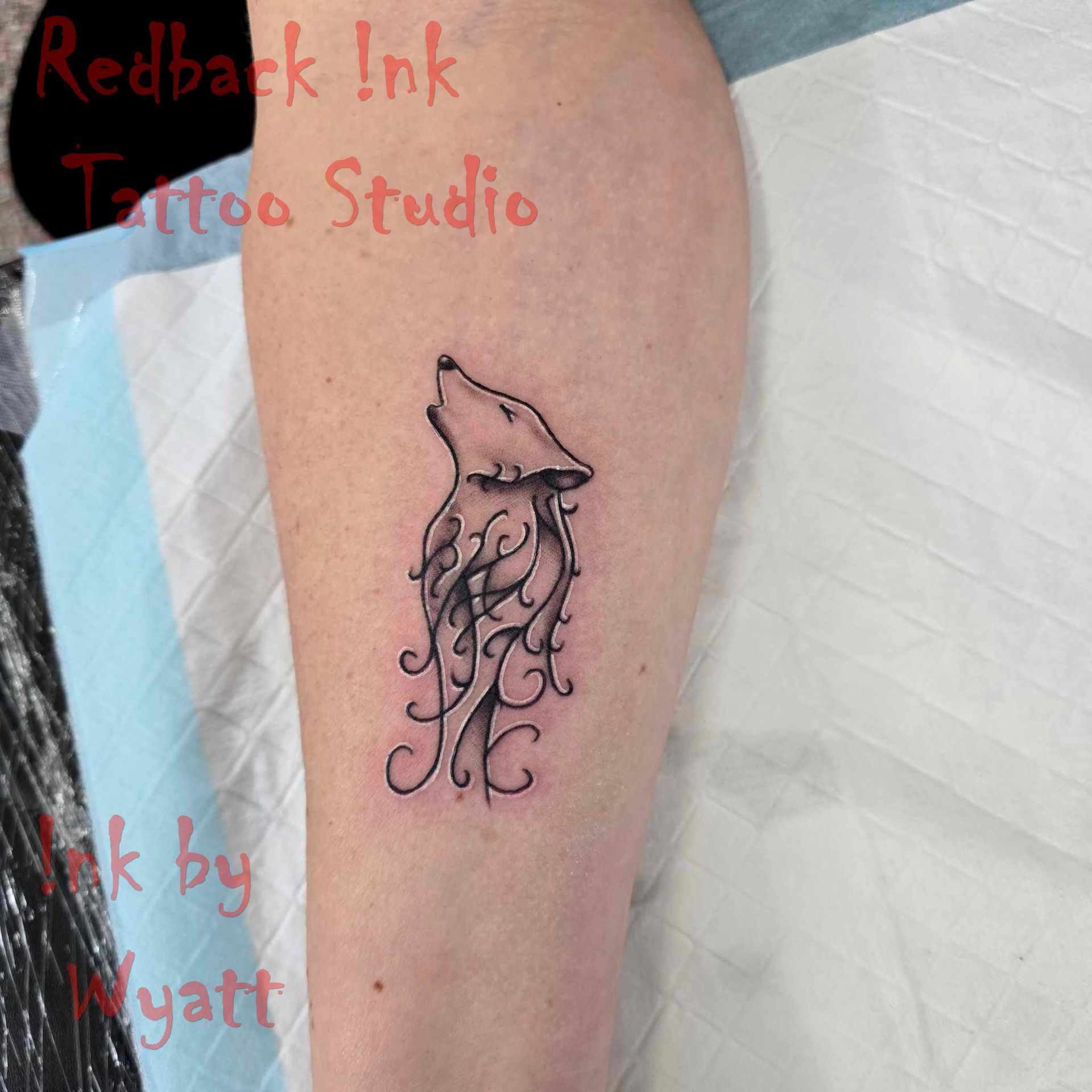 Tattoo of a Howling Wolf With Swirling Vines on a Person's Arm — Redback !nk Tattoo Studio in Kawana, QLD
