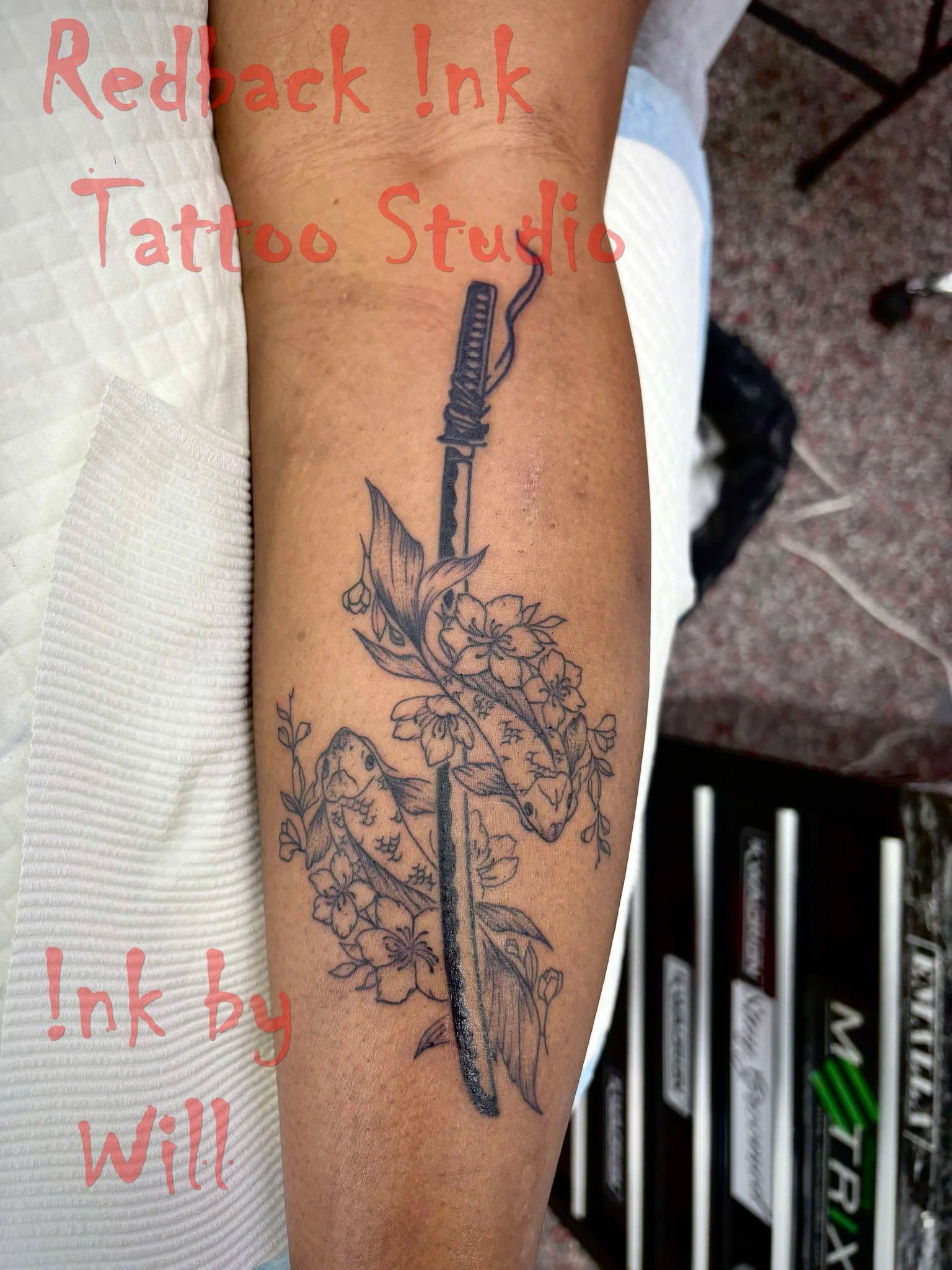 Tattoo of a Katana Sword Piercing Through Floral Branches on a Person's Forearm — Redback !nk Tattoo Studio in Kawana, QLD